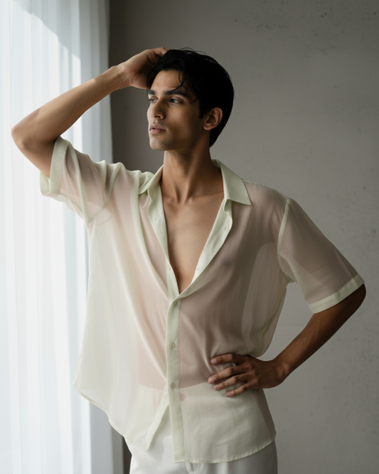 Man wearing a sheer white shirt with a blurred background
